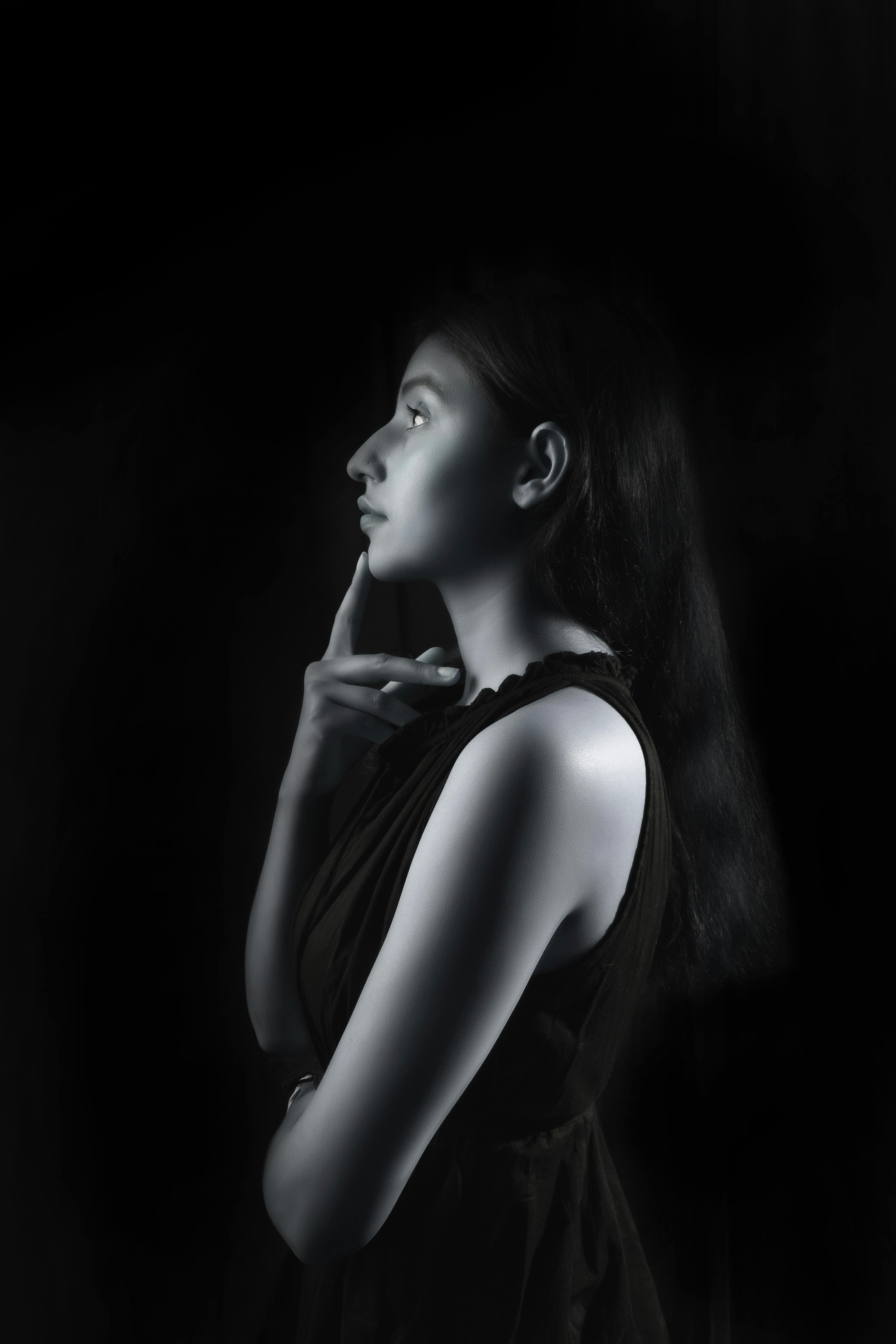Black and white profile portrait of a woman posing in a studio setting, showcasing elegant shadows and lighting.