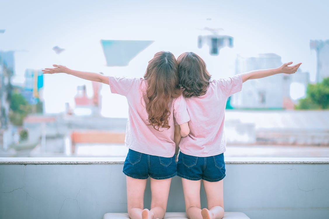 Free Two Girls Spreading Arms Together While Kneeling Stock Photo