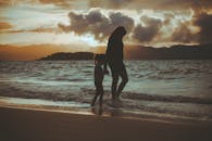 日落时分，一对母子沿着弗洛里亚诺波利斯海滩散步，在海浪的映衬下，他们的身影形成了宁静的背光轮廓