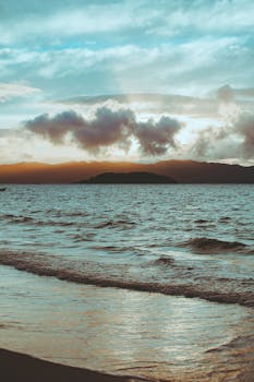宁静的海浪中，日出景象映照着云层和遥远的陆地
