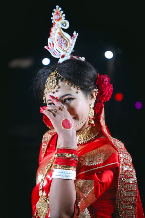 Free Portrait of a smiling Bengali bride in a red saree with traditional makeup and jewelry Stock Photo