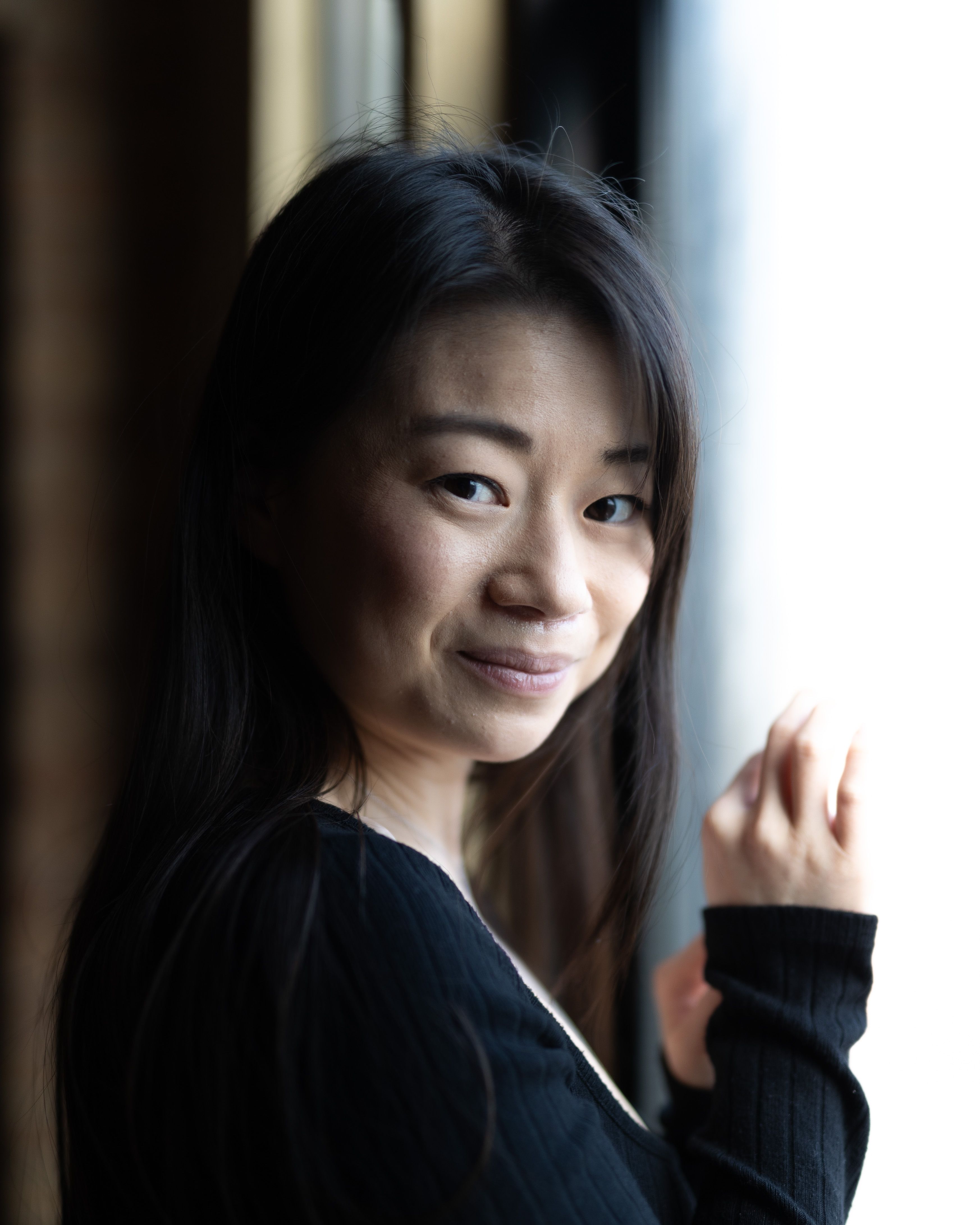 Portrait of a smiling woman with long hair by a window in Chicago, USA.