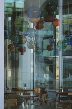 Chic urban cafe interior featuring vibrant glass lamps and stylish wooden furniture.