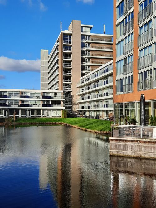Free Stylish apartment buildings reflected in a canal under a bright blue sky in Alphen aan den Rijn, Netherlands. Stock Photo