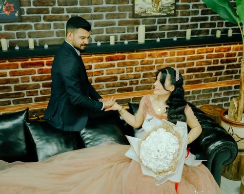 Free A bride and groom share a romantic moment indoors with a bouquet of white roses. Stock Photo