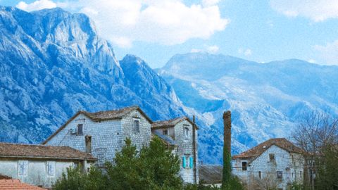 Charming village houses set against a stunning mountain landscape under a bright sky.