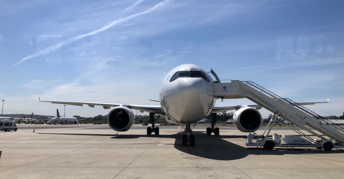 Front view of a commercial airplane on the runway at Lisbon Airport under a clear sky.
