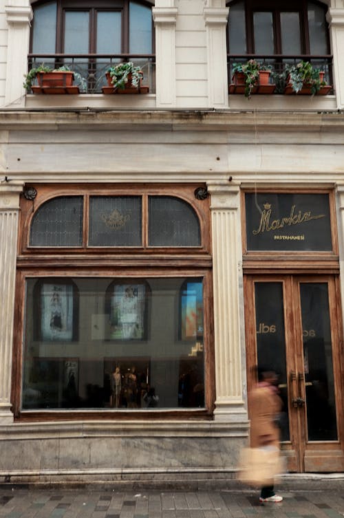 A woman walking past a building with a window