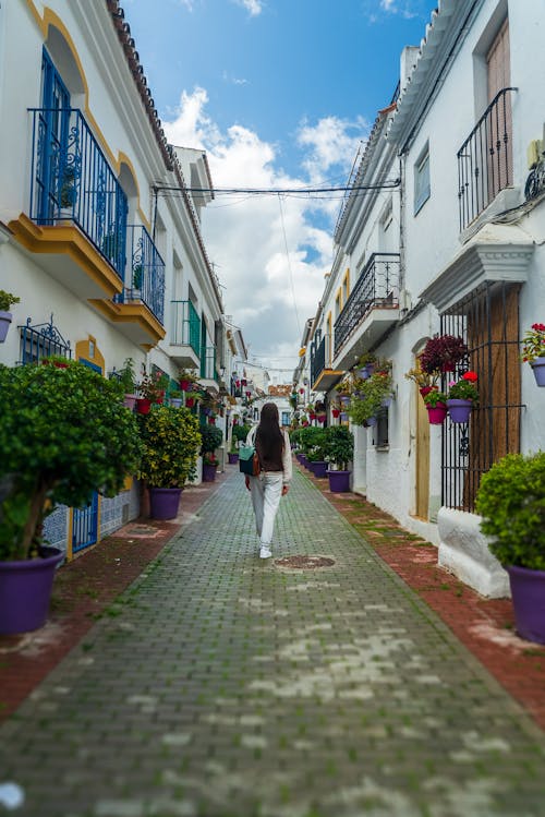 A woman walking down a narrow street in a town