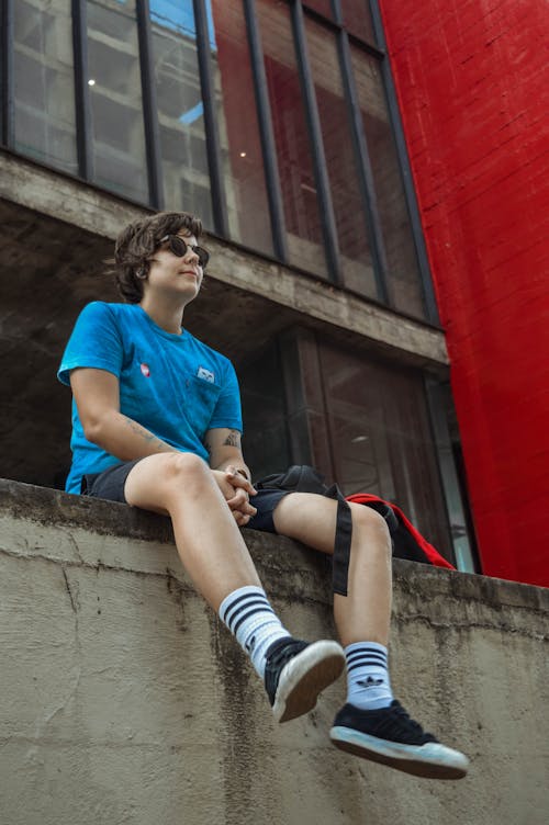 Free Man in Blue Crew-neck T-shirt Sitting on Grey Concrete Pavement Stock Photo