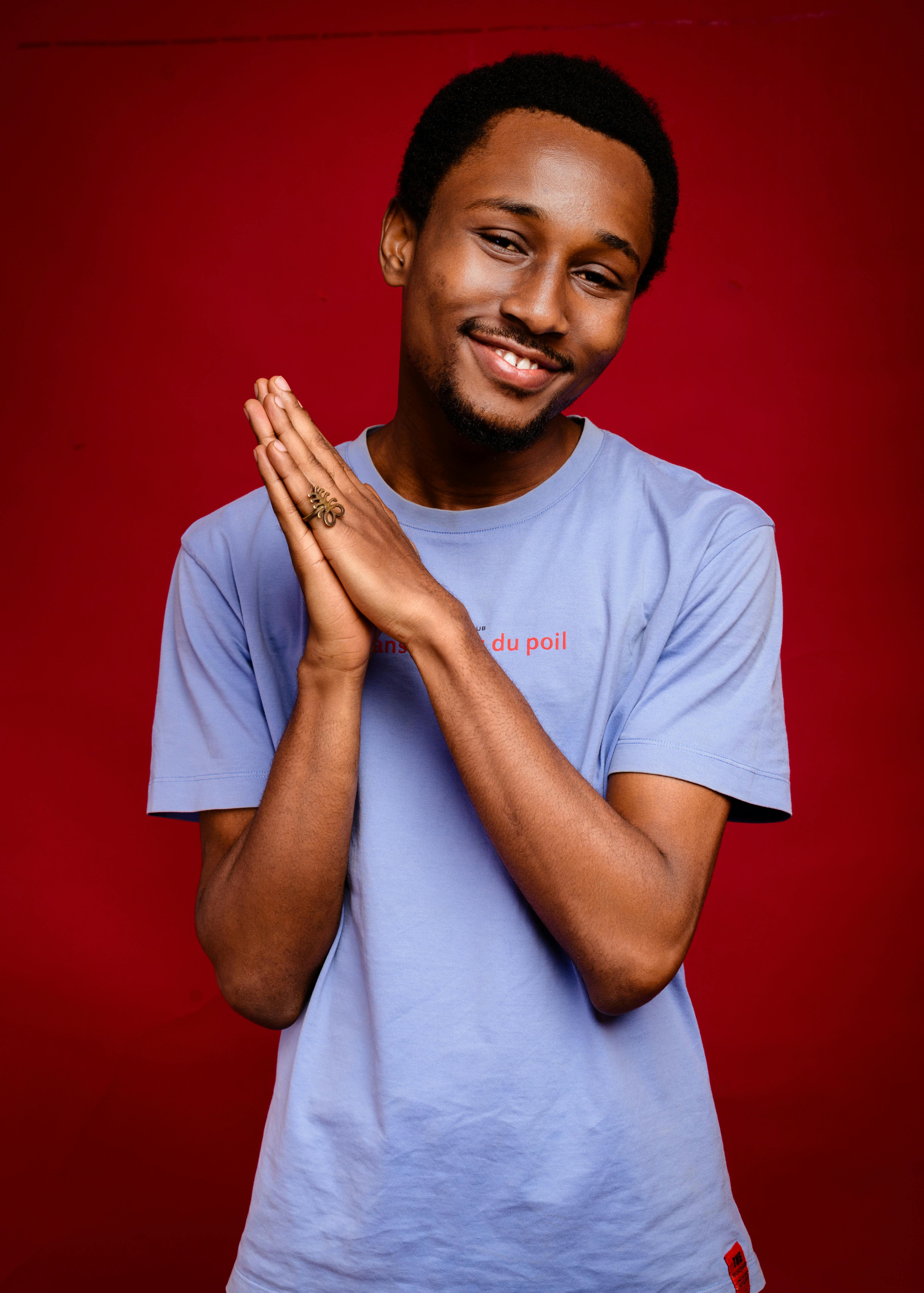 Portrait of a smiling man in a purple T-shirt against a vibrant red background in a studio shoot.
