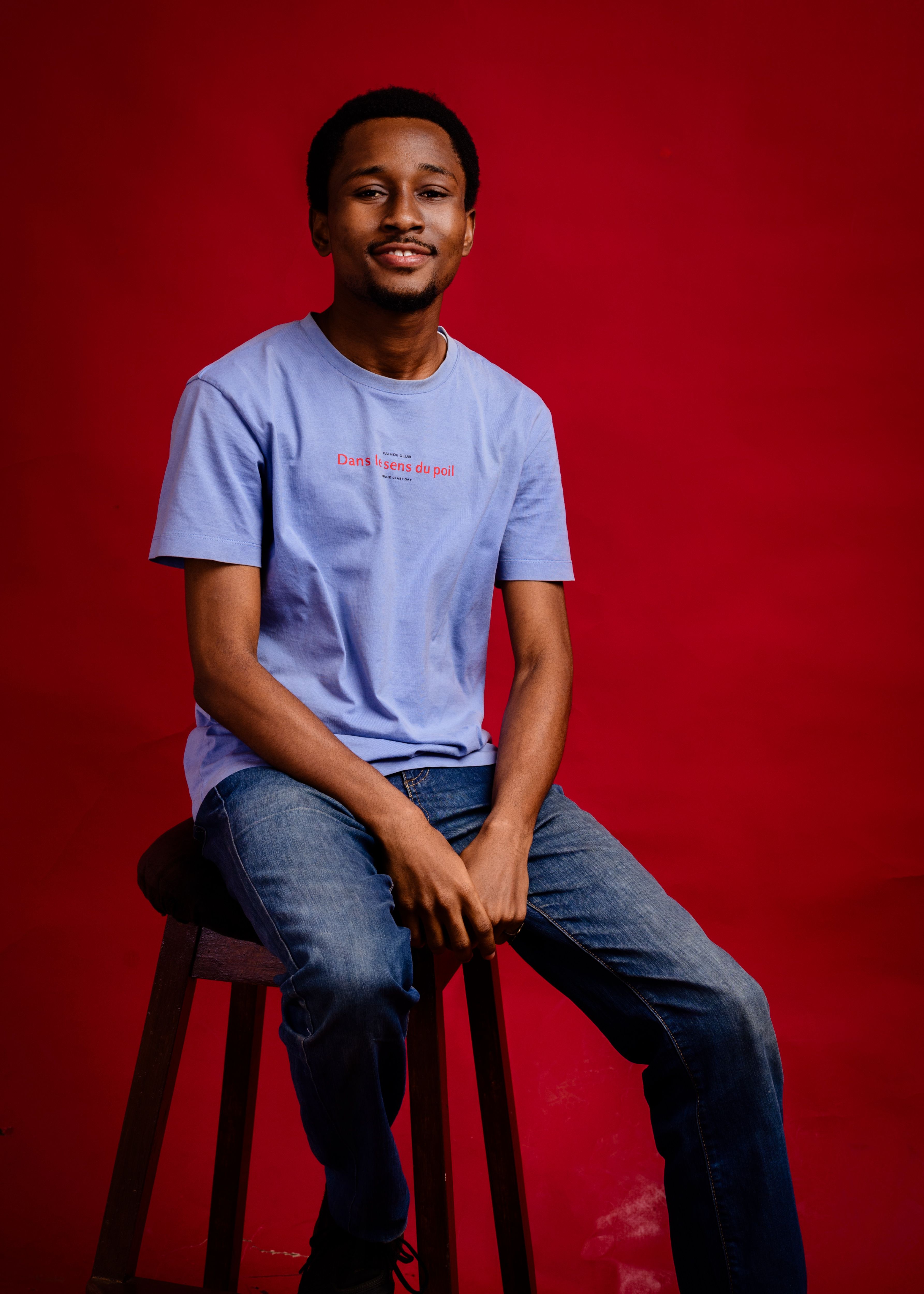 Stylish portrait of a man in casual wear against a red backdrop.