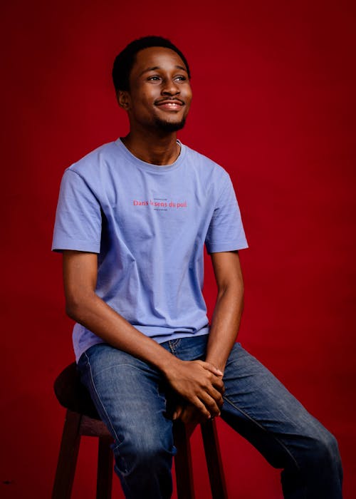 A young man sitting on a stool in a blue shirt