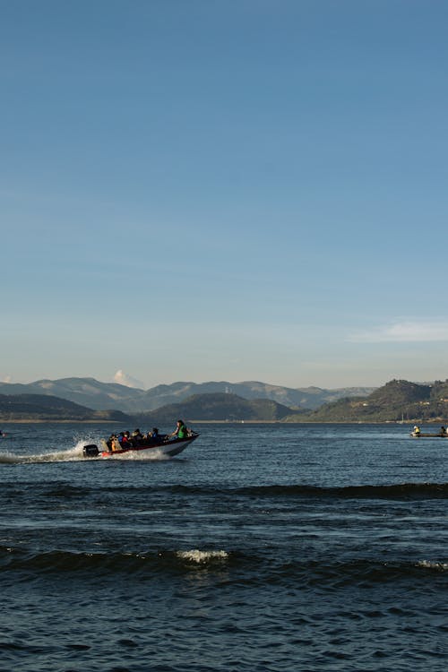 A boat is traveling on the water with mountains in the background