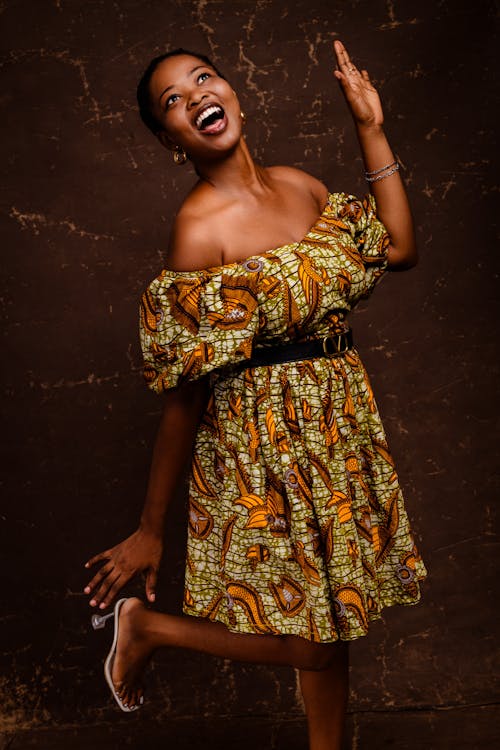 A woman in an african print dress is smiling