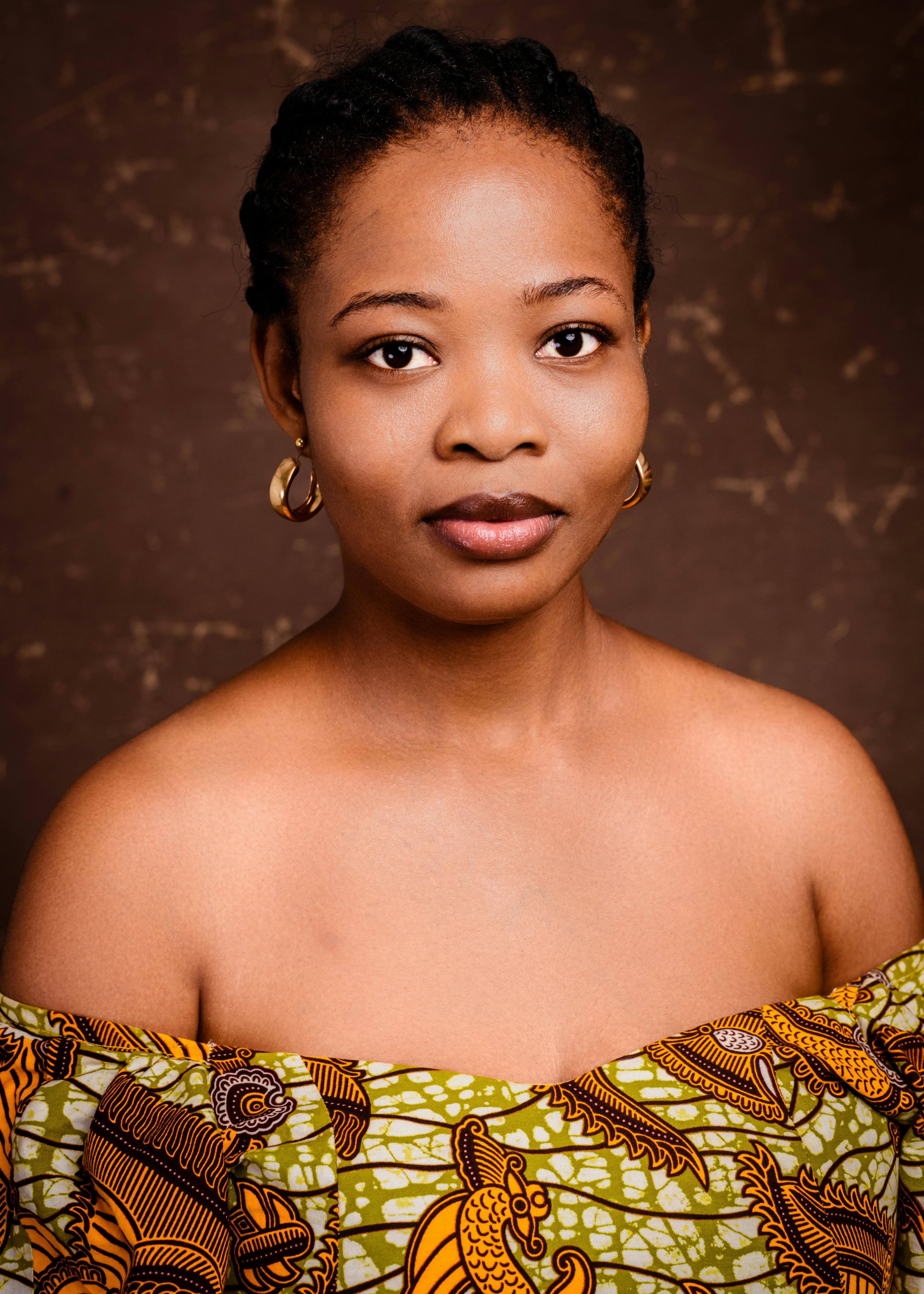 Captivating studio portrait of a woman wearing vibrant African print dress, showcasing elegance and style.