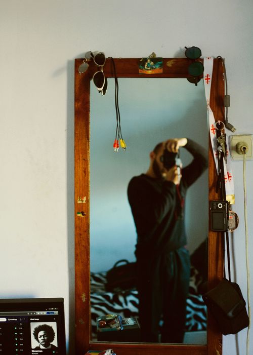 Free A person stands before a mirror, capturing a reflective self-portrait in a cozy room. Stock Photo