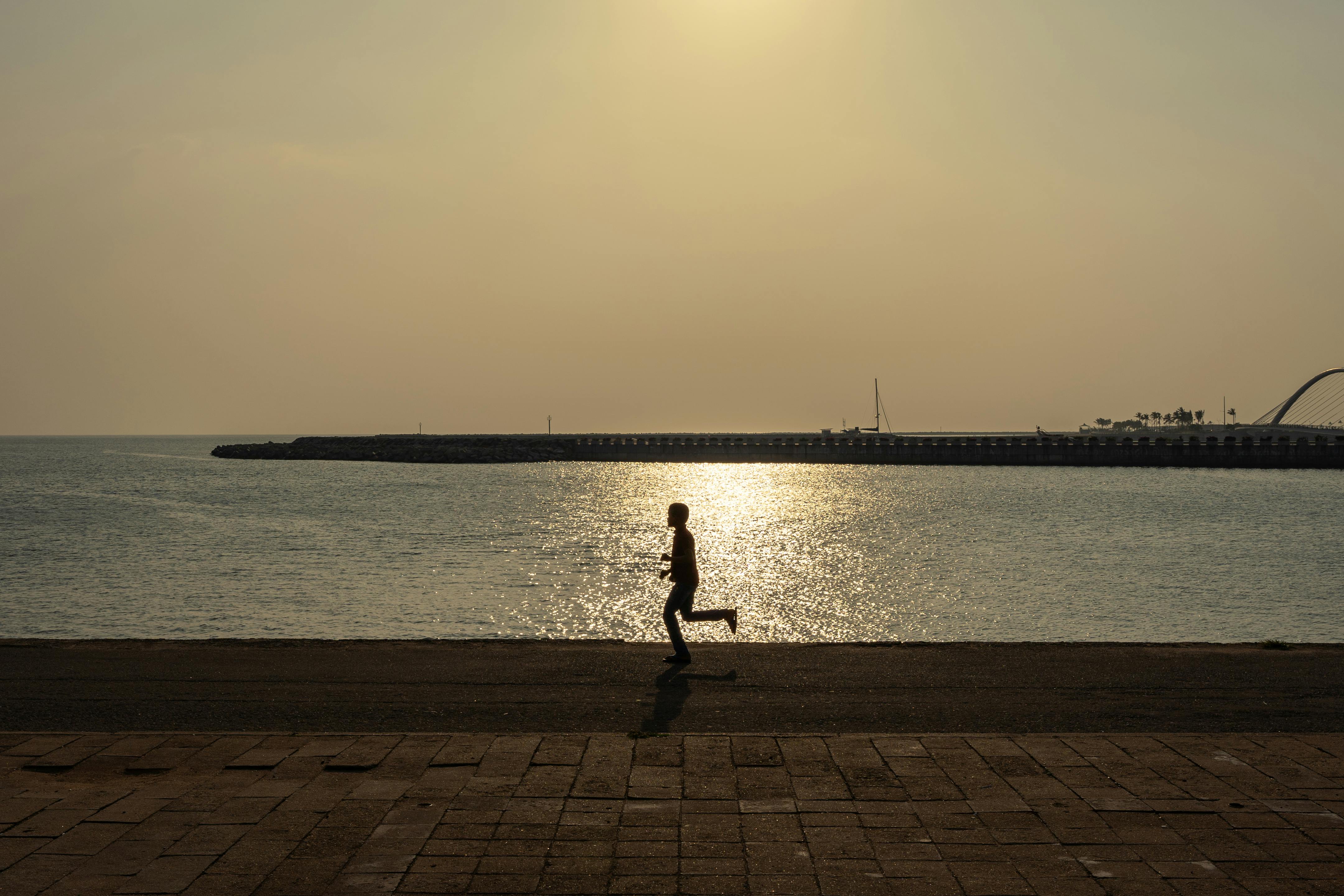 man running on promenade on sea shore