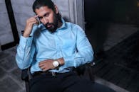 一个穿着蓝色衬衫的时尚男人坐在室内，肖像散发出严肃而现代的氛围