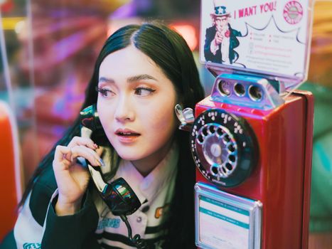 Young woman using a vintage payphone in a retro-style setup, adding a nostalgic vibe.