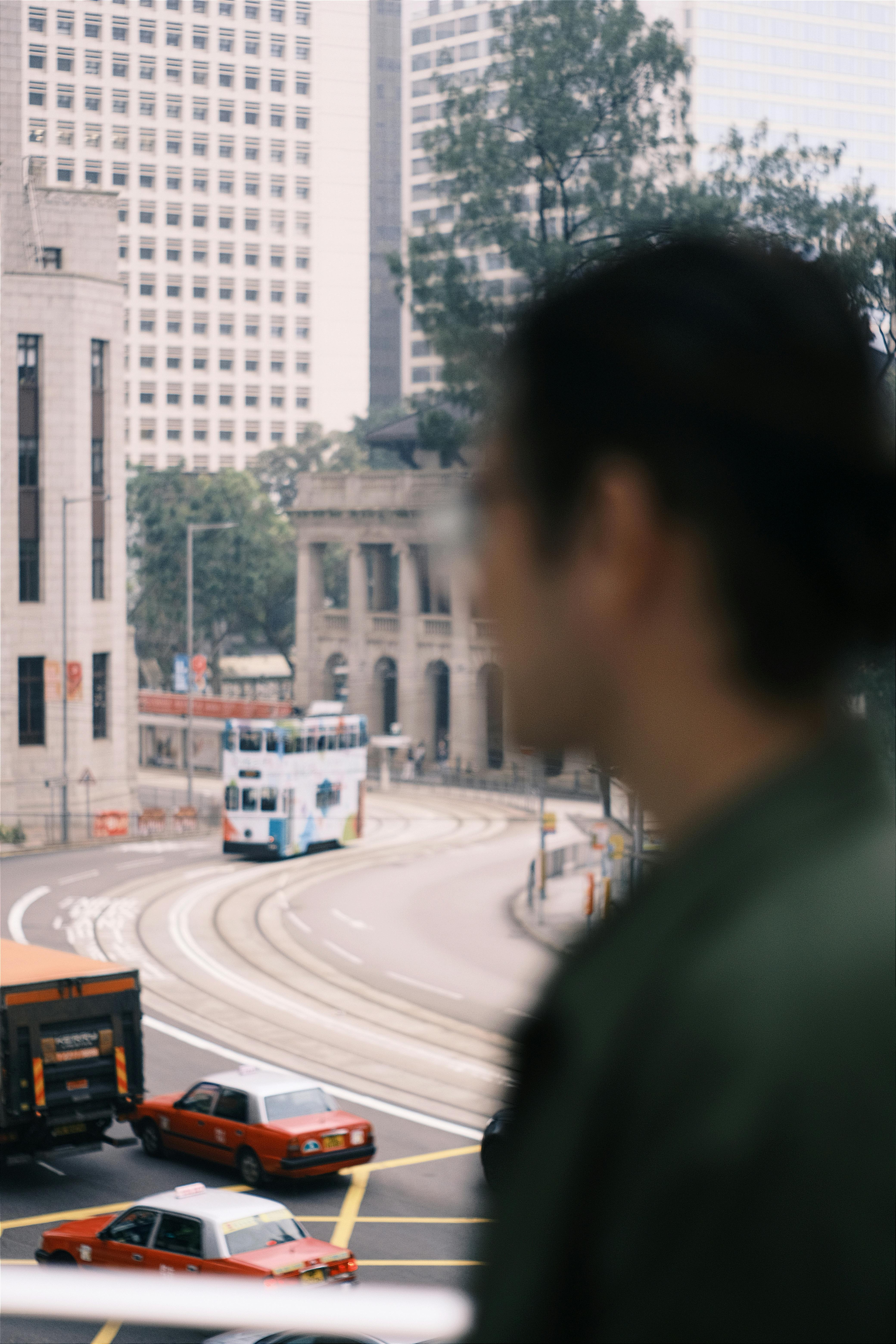 A city street scene featuring a tram, taxis, and a silhouette of a person in Hong Kong.