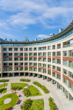 Aerial view of a modern curved building surrounding a green urban courtyard.