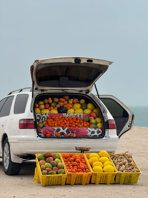 A car with fruit in the trunk and crates of fruit