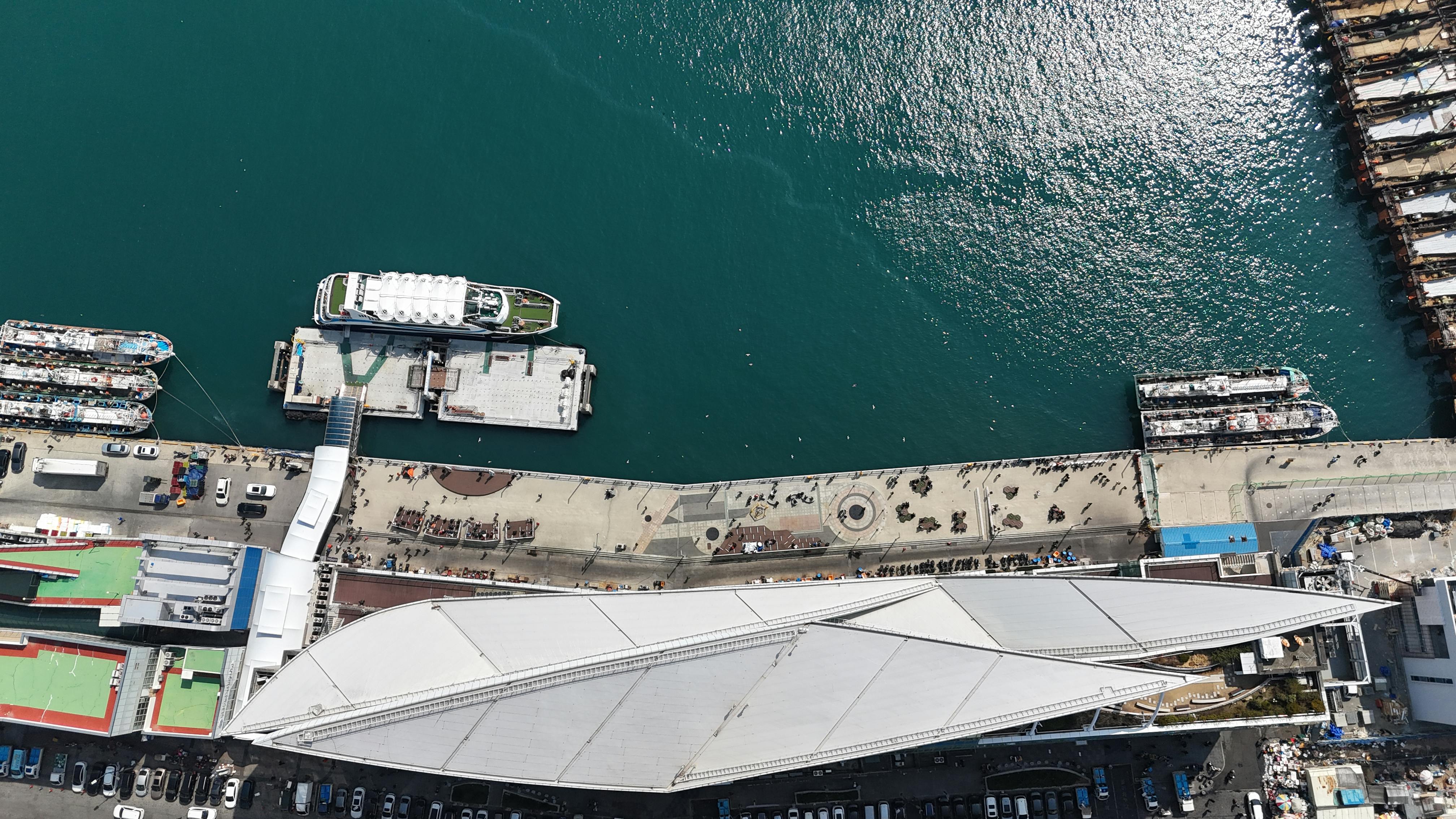 Aerial shot of Busan port showcasing ships at the pier and bustling urban activity.