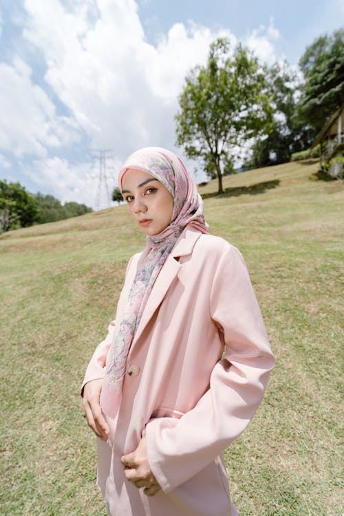 A woman in a pink coat stands in a field