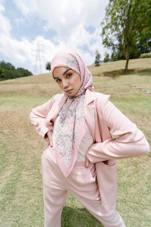 A woman in pink suit and hijab posing for the camera