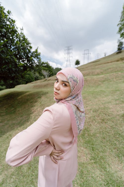 A woman in a pink hijab posing in the grass