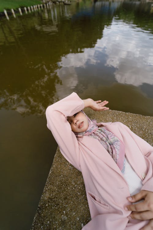 A woman laying on the ground near a body of water