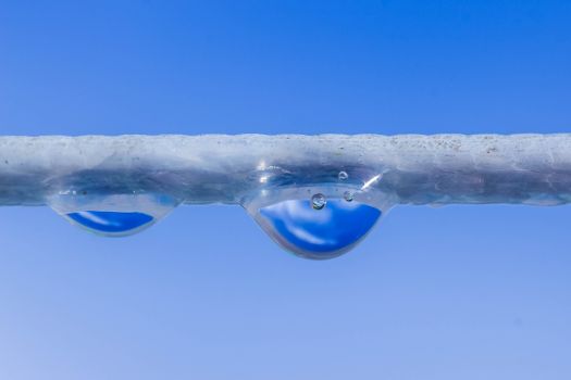 Macro shot of water droplets hanging on a rope against a clear blue sky.. macro, shot, water