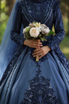 Bride in intricately designed blue gown holding a floral bouquet, perfect for pre-wedding themes.