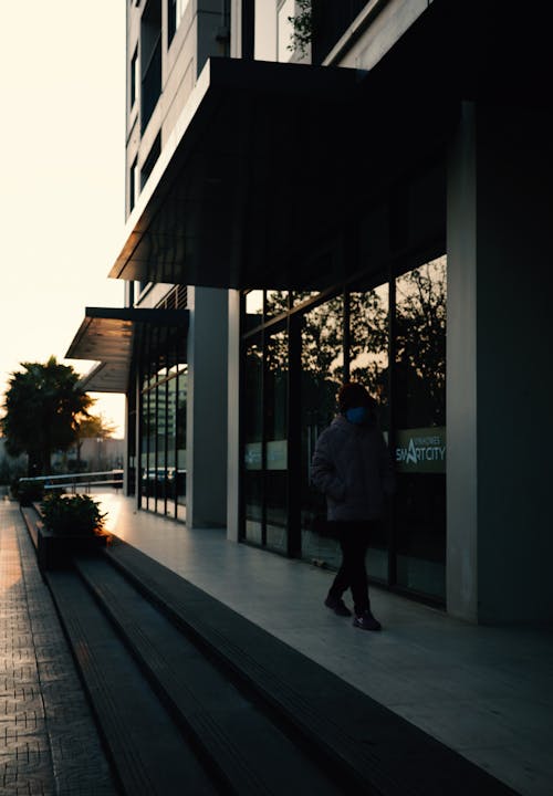 A person walking down a sidewalk at sunset