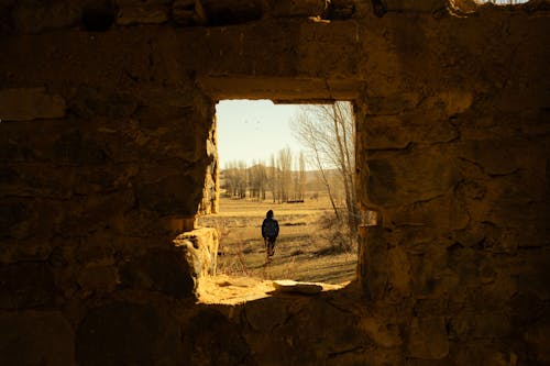 A person walking through a window in a stone building