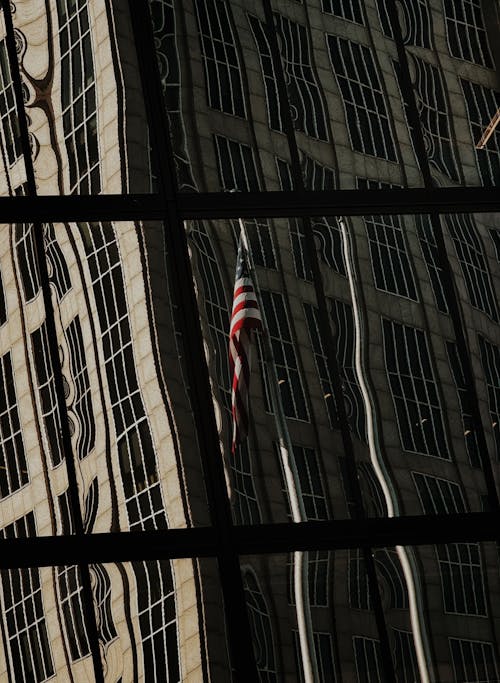 A reflection of a building in a window with an american flag