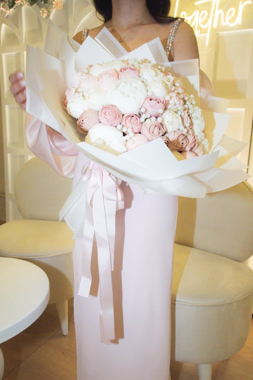 Free A woman in a pink dress holding a bouquet of flowers Stock Photo