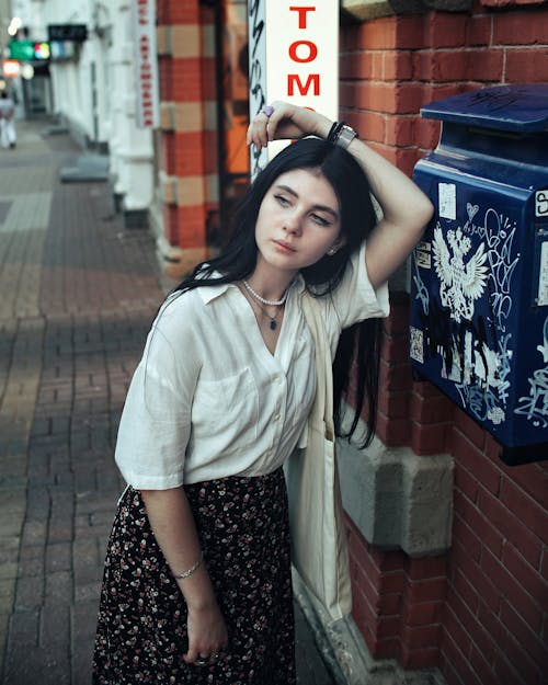 A woman leaning against a mailbox with a sign that says to