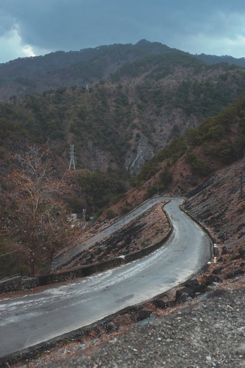 A curved road in the mountains with a mountain in the background
