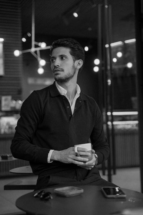 Free A man in a black and white photo sitting at a table Stock Photo