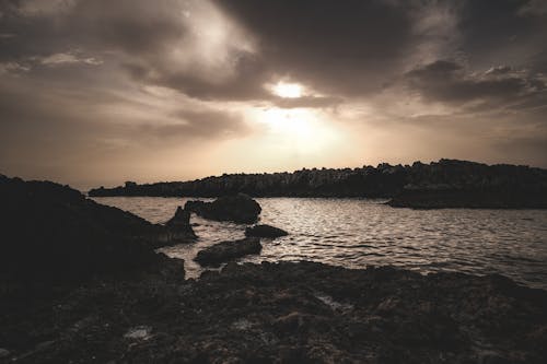 A sunset over the ocean with rocks and clouds