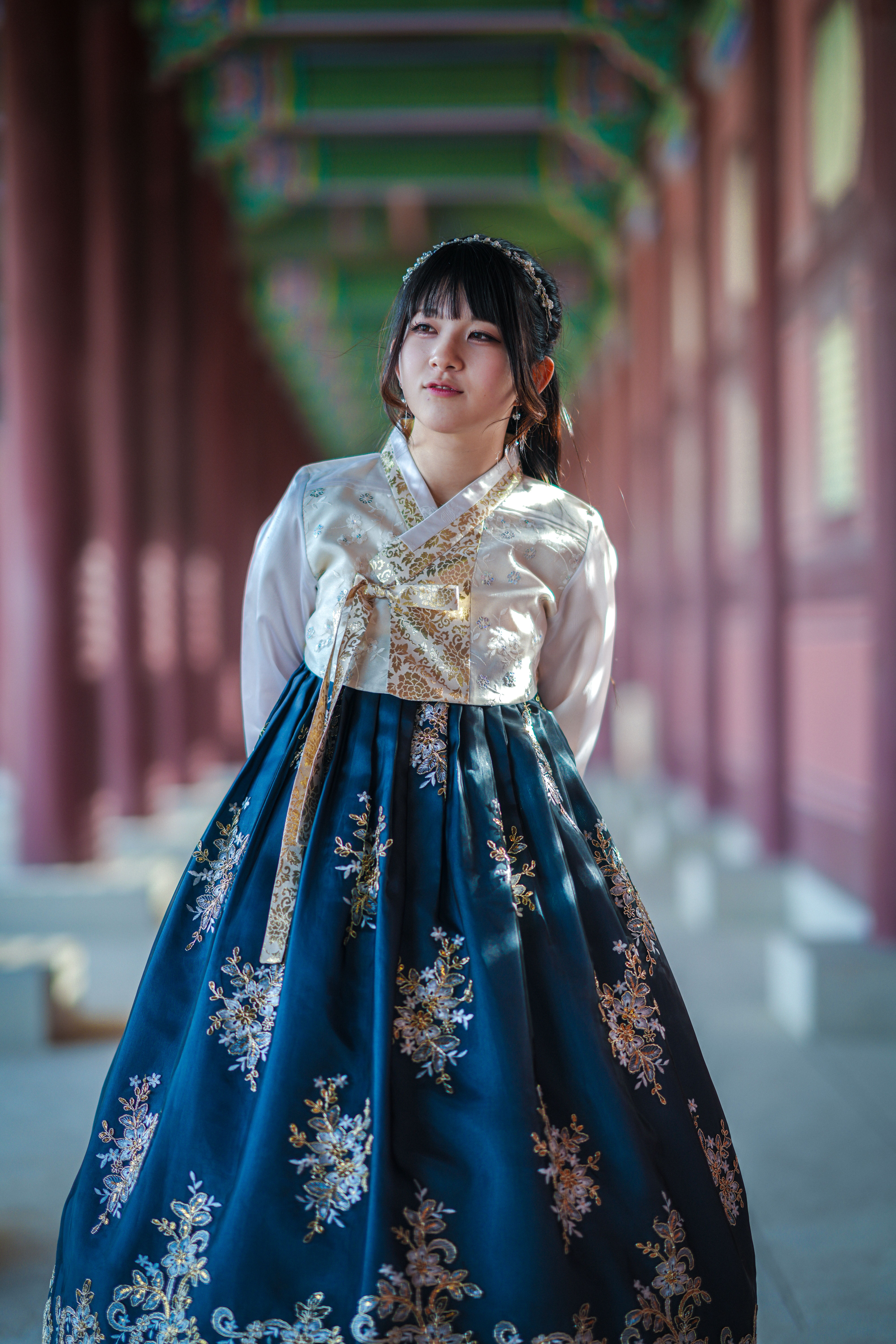 A woman in a traditional Korean hanbok stands elegantly at Gyeongbokgung Palace.