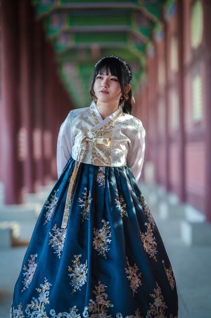 A woman in a traditional Korean hanbok stands elegantly at Gyeongbokgung Palace.