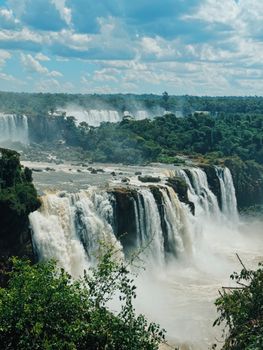 Breathtaking scene of Iguazu Falls with lush rainforest under clear skies.