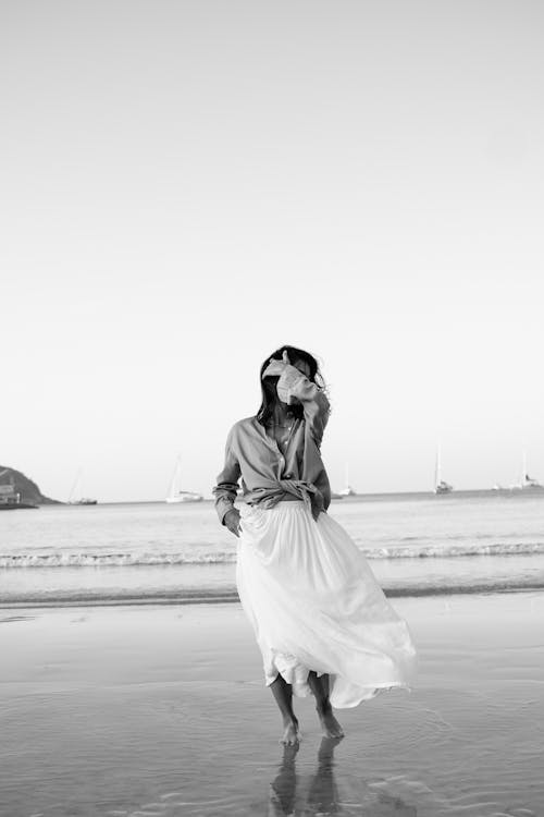 A woman in a skirt walking on the beach