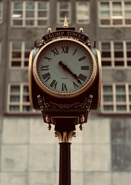 A clock on a pole in front of a building