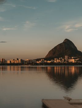 Breathtaking view of Rio de Janeiro's skyline and Sugarloaf Mountain at sunset, reflecting on calm waters.