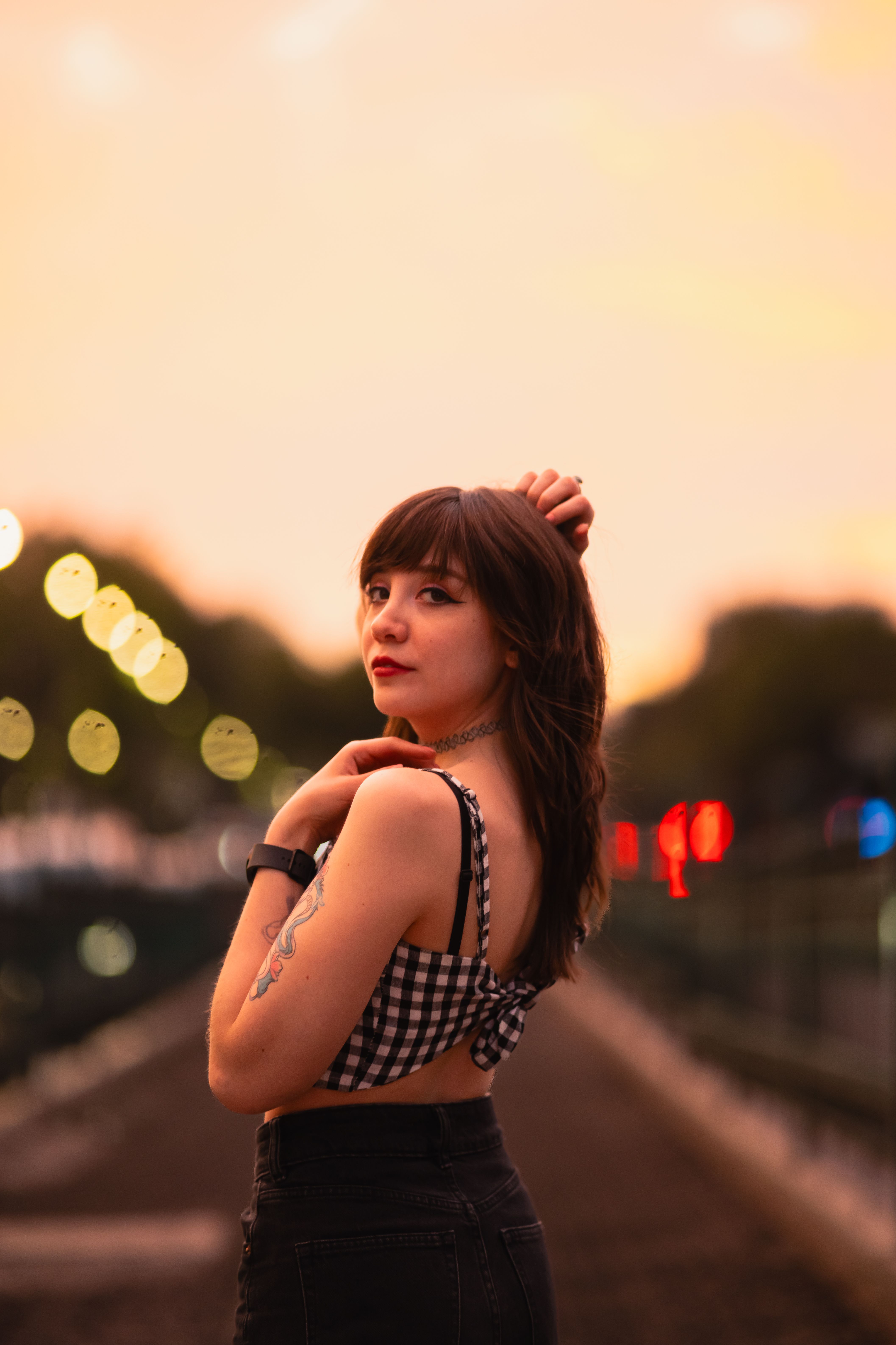 Young woman posing at sunset in an urban environment, wearing a checkered crop top.