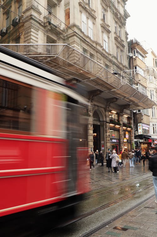 A red and white train is moving down a street